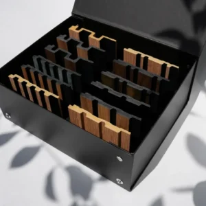 Detailansicht eines schwarzen Musterkoffers gefüllt mit Holz-Wandpaneelen in verschiedenen Designs und Farben, präsentiert für Architekten und Innenarchitekten zur Auswahl von Materialien für die Raumgestaltung.